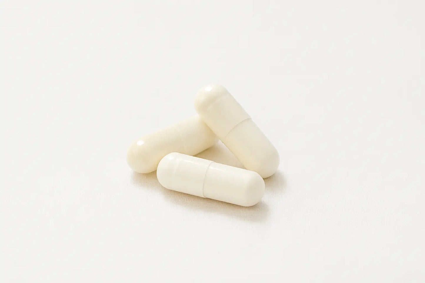 Три бели капсули с екстракт от ганодерма и лечебни гъби върху бял фон