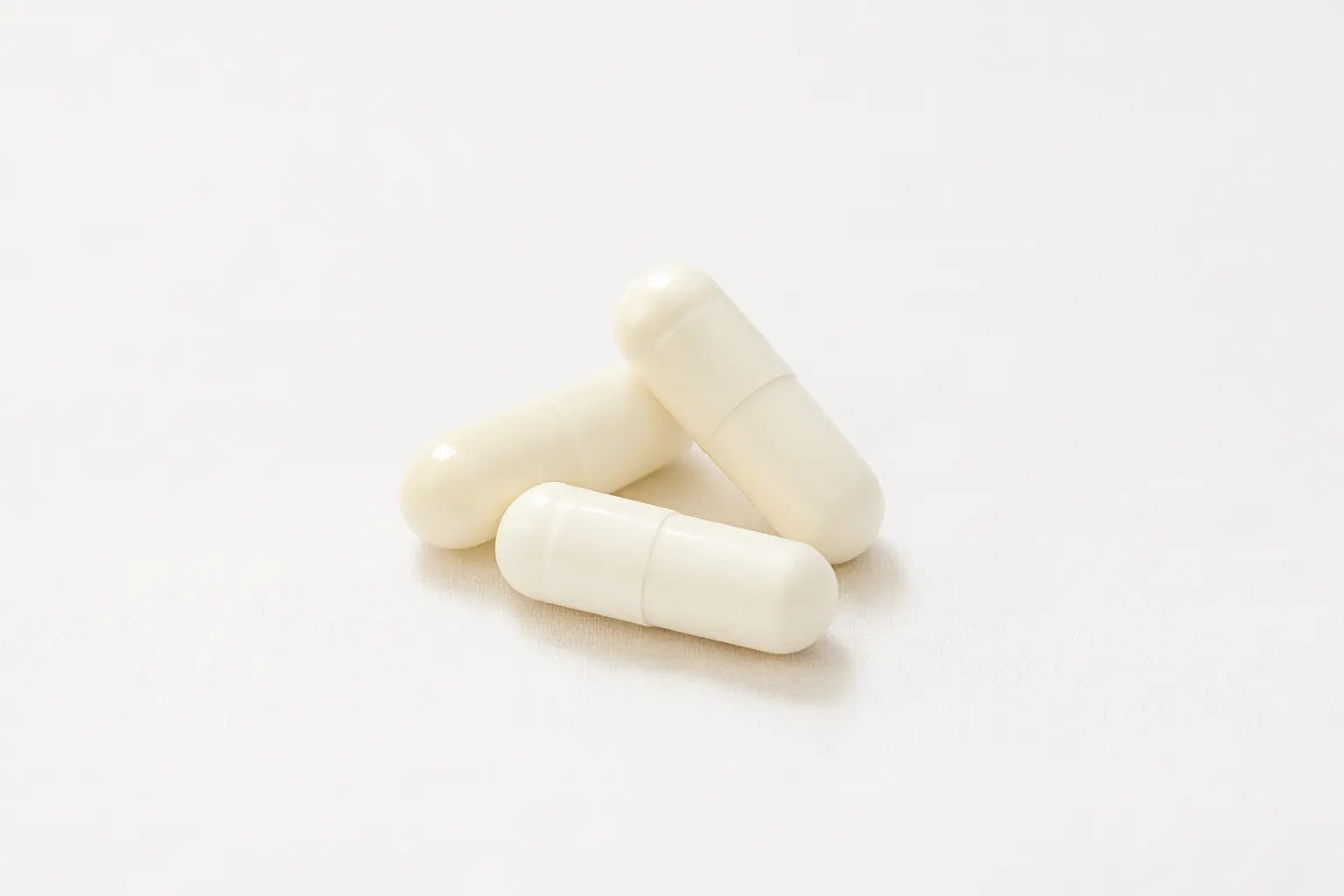 Три бели капсули с екстракт от ганодерма и лечебни гъби върху бял фон