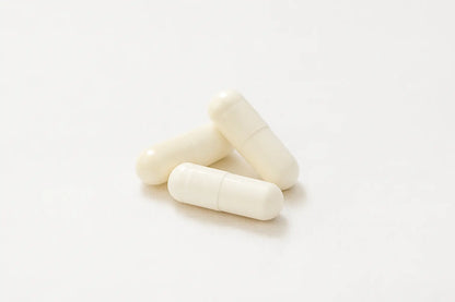 Три бели капсули с екстракт от ганодерма и лечебни гъби върху бял фон