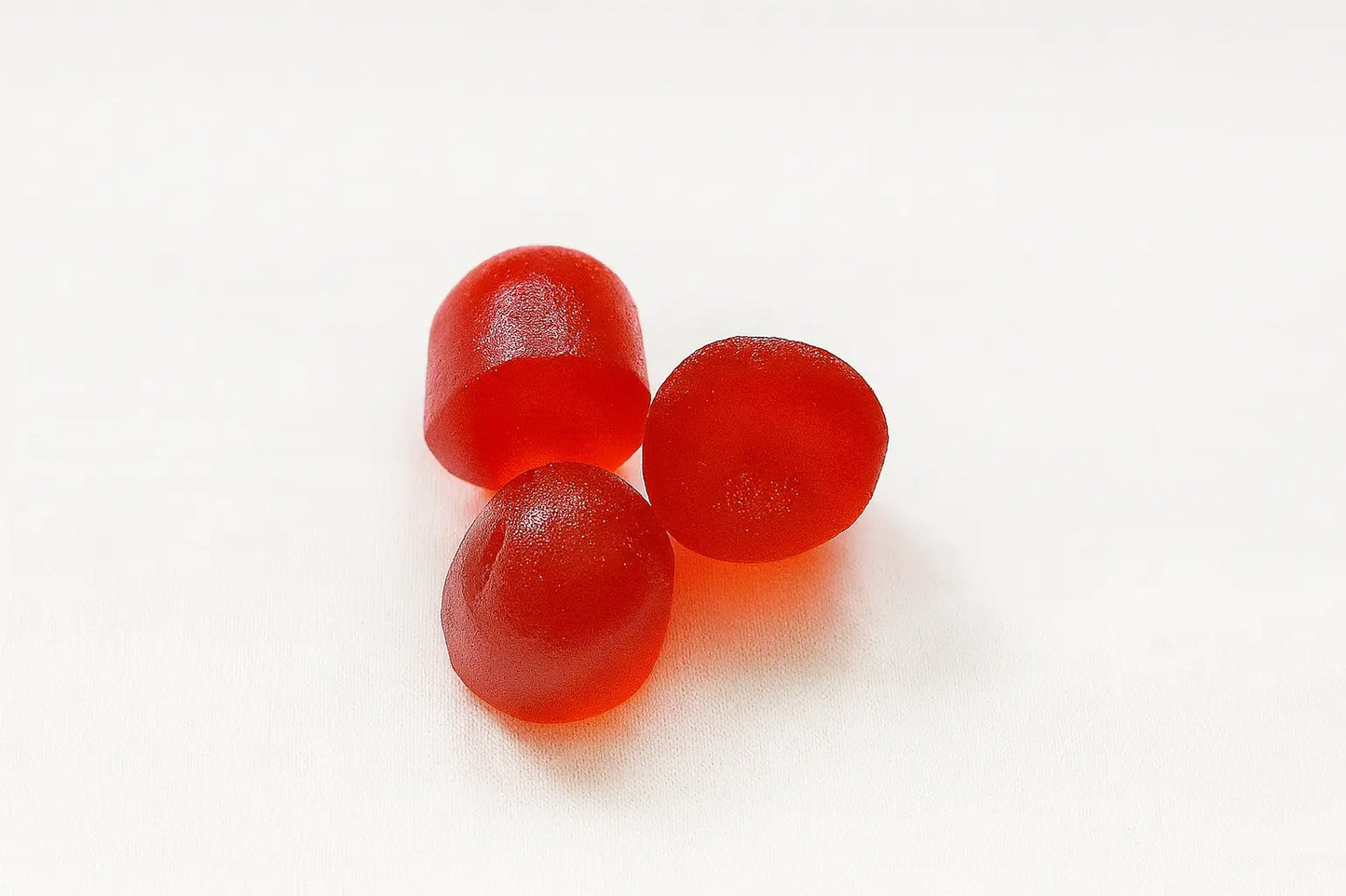 Три червени желирани бонбона с лечебни гъби върху бял фон